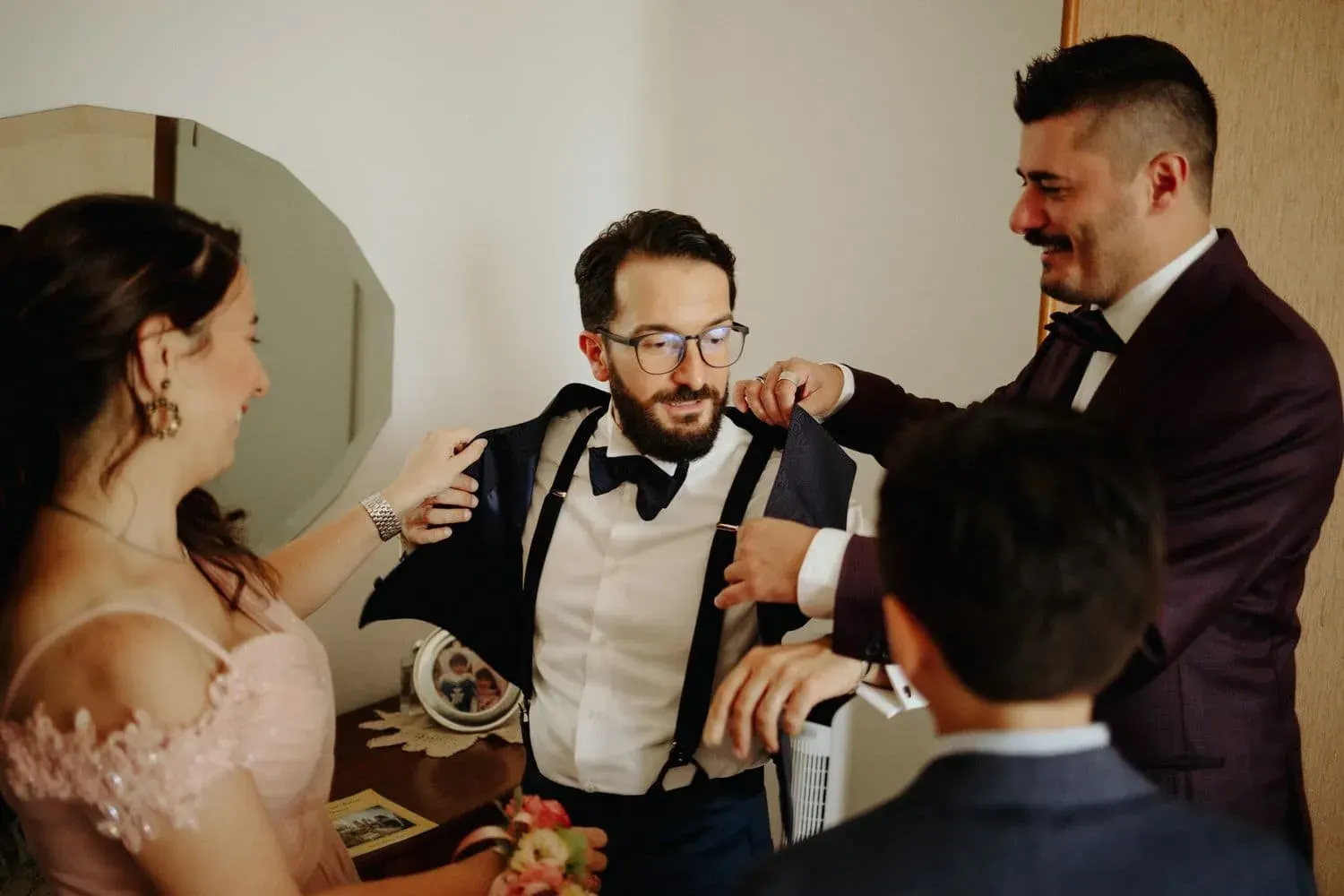 Lo sposo aiutato dagli amici durante la vestizione