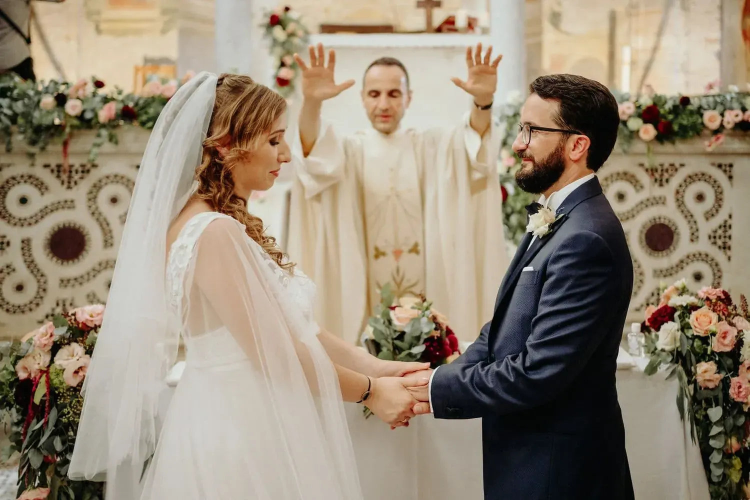Gli sposi si tengono per mano davanti al celebrante