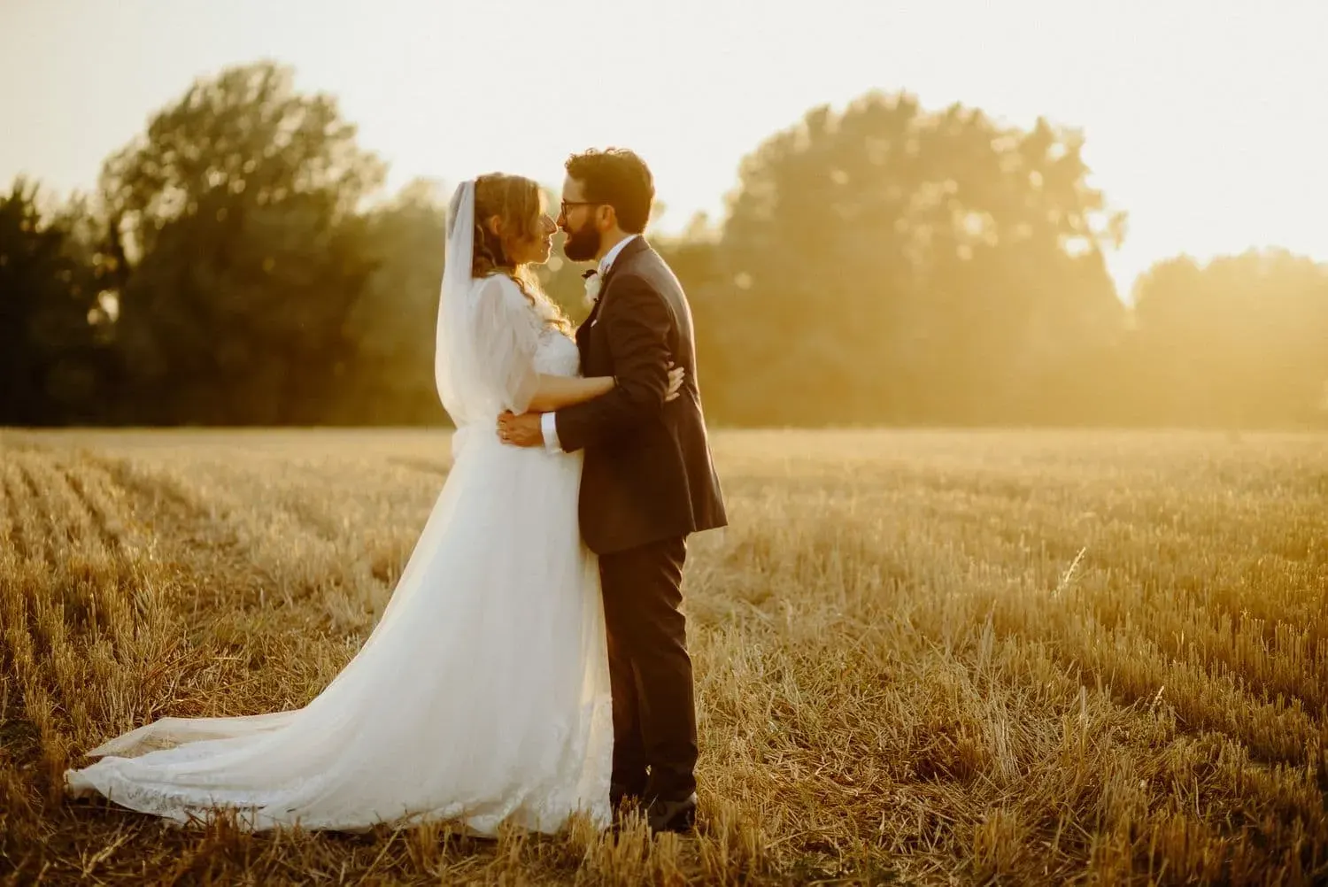 Il bacio degli sposi nel campo al tramonto