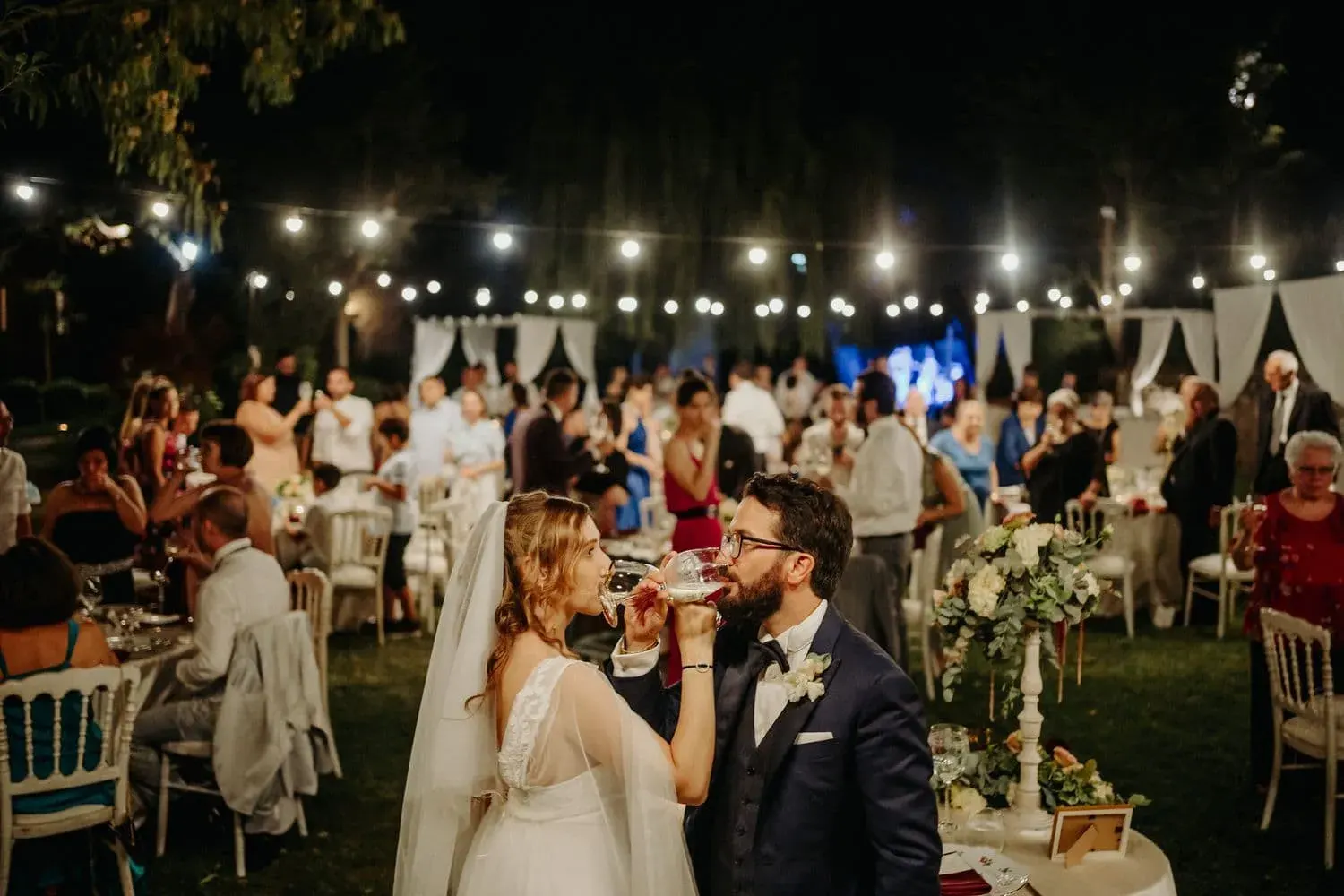 Gli sposi tra i tavoli durante la cena in giardino
