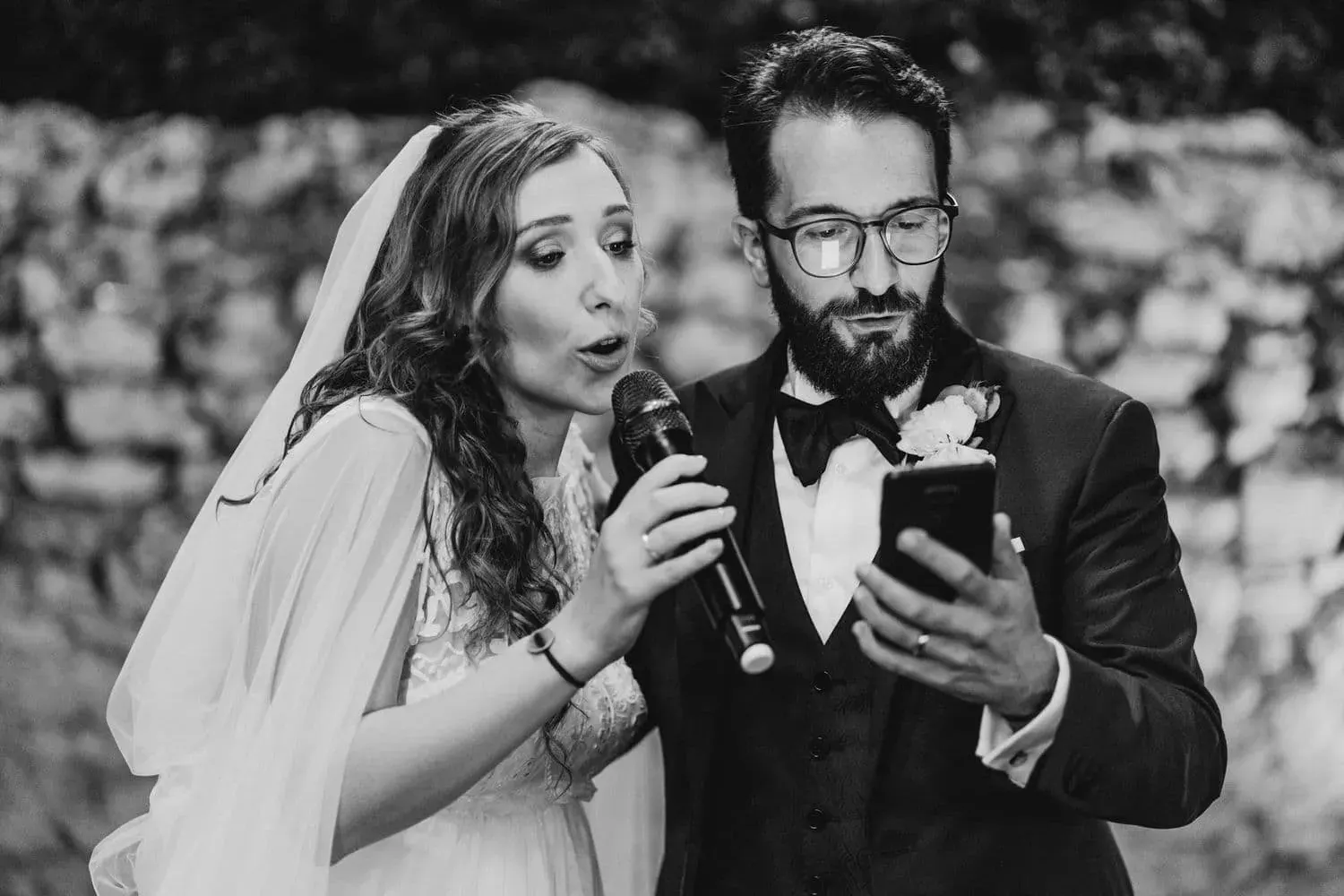Gli sposi cantano insieme al microfono, in bianco e nero