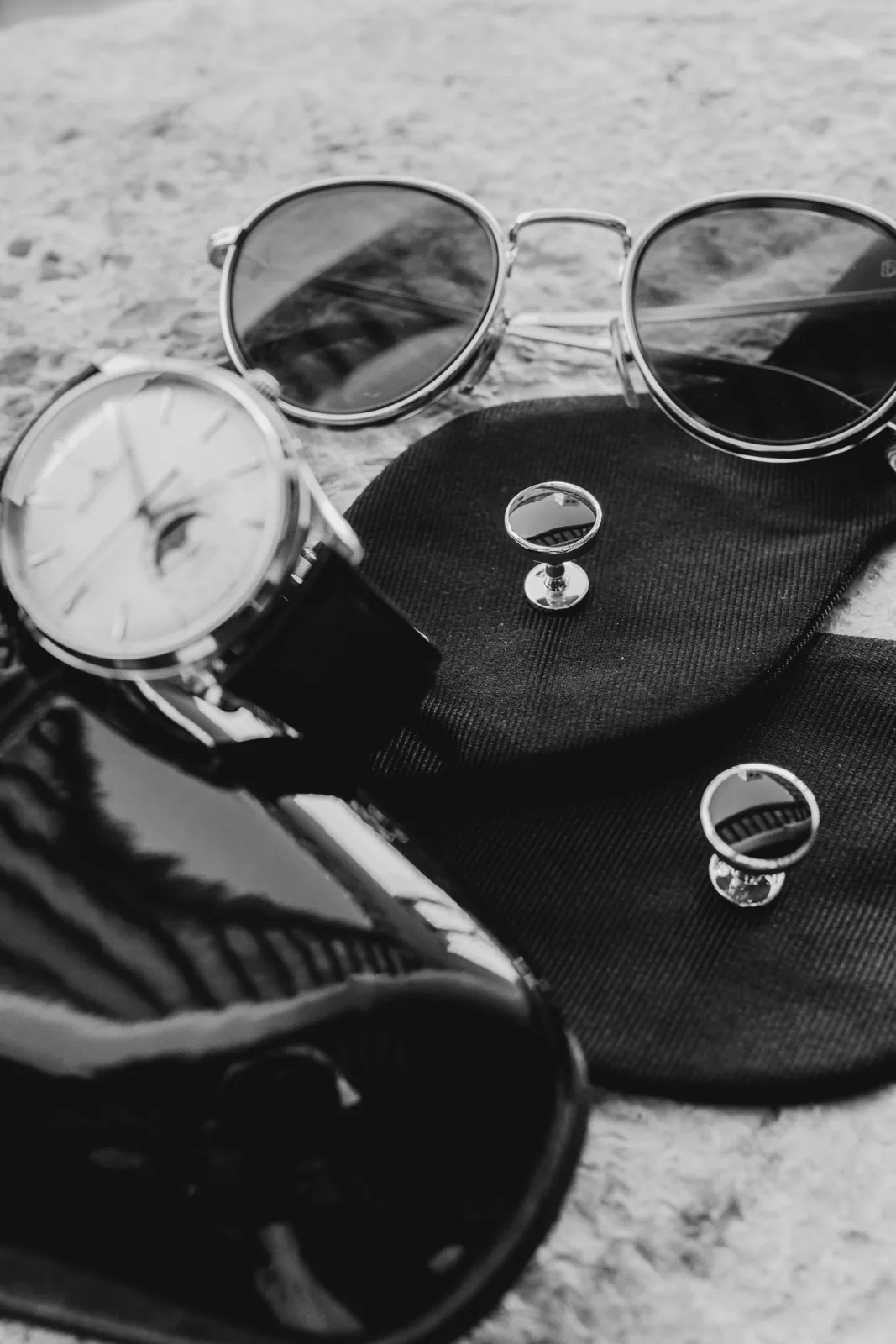Dettagli dello sposo: orologio, occhiali da sole e gemelli, in bianco e nero
