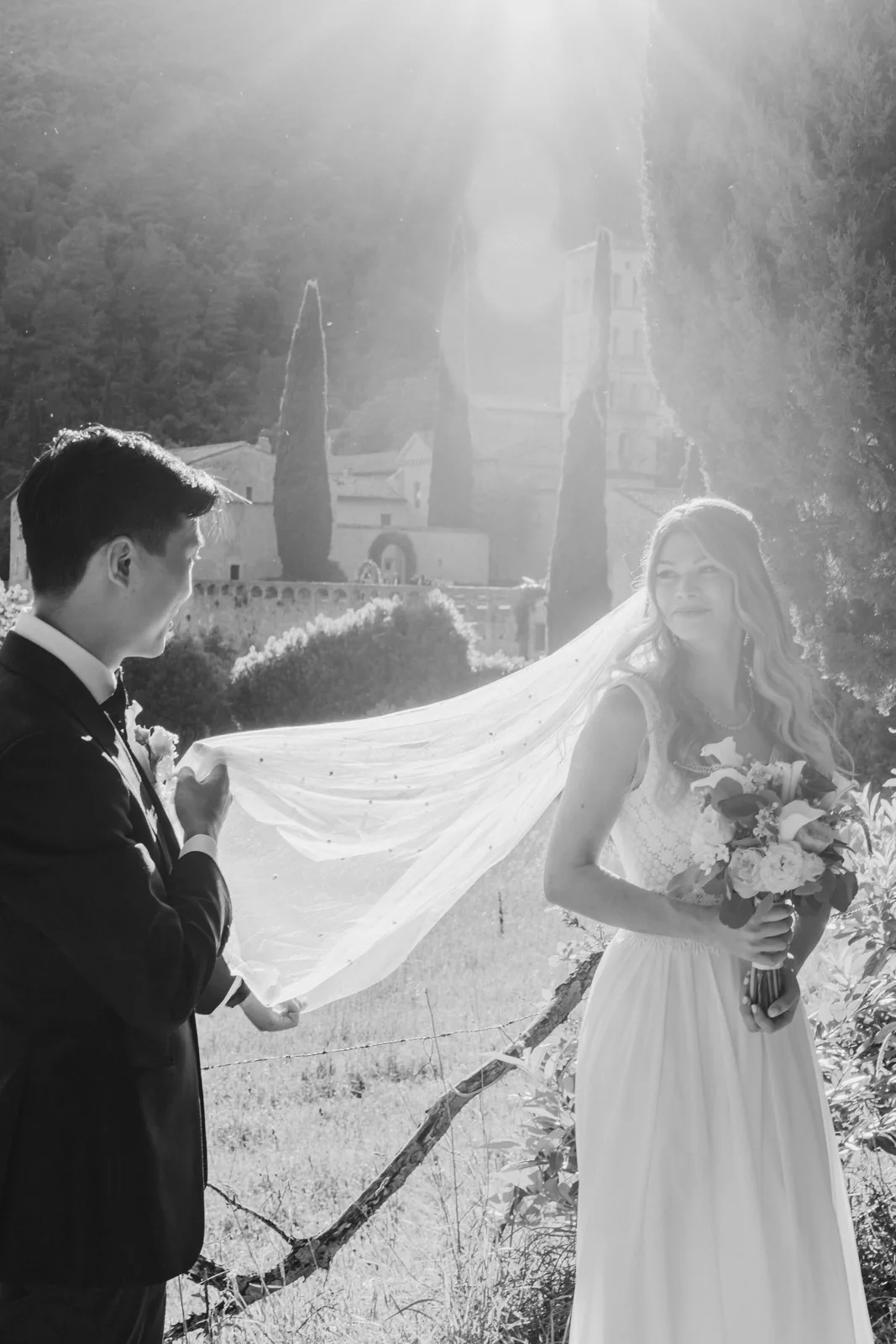 Lo sposo solleva il velo della sposa in controluce, in bianco e nero