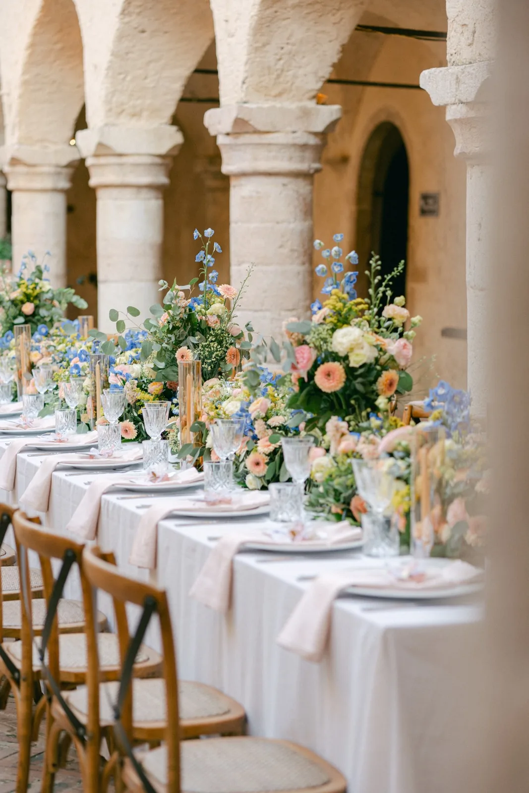 La tavola apparecchiata nel chiostro dell’Abbazia San Pietro in Valle, con fiori pesca e azzurri