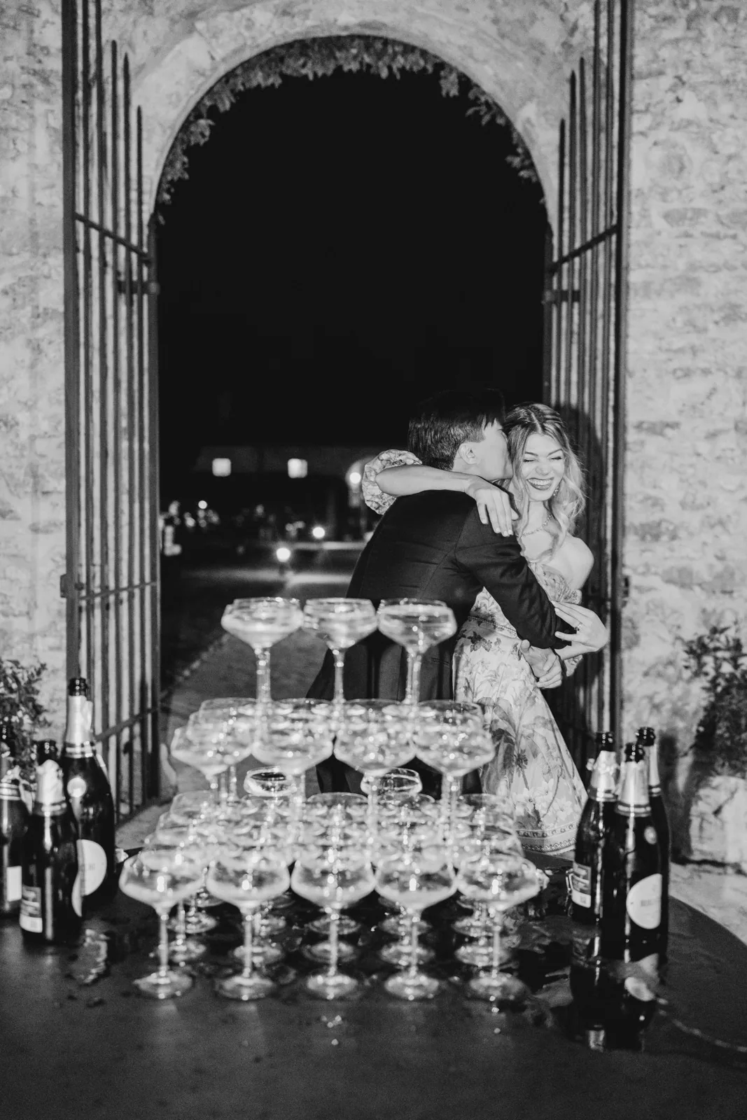 L’abbraccio degli sposi dietro la champagne tower, in bianco e nero