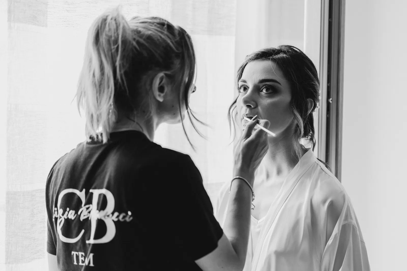Il trucco della sposa davanti alla finestra, in bianco e nero