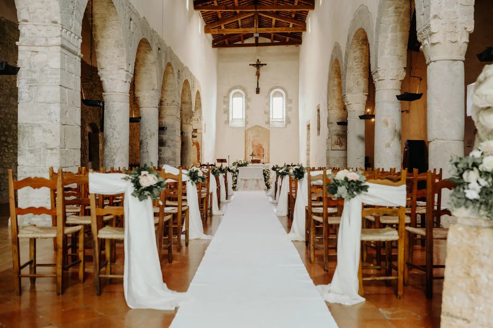 La navata della chiesa di San Nicolò a San Gemini con la passatoia bianca e i fiori