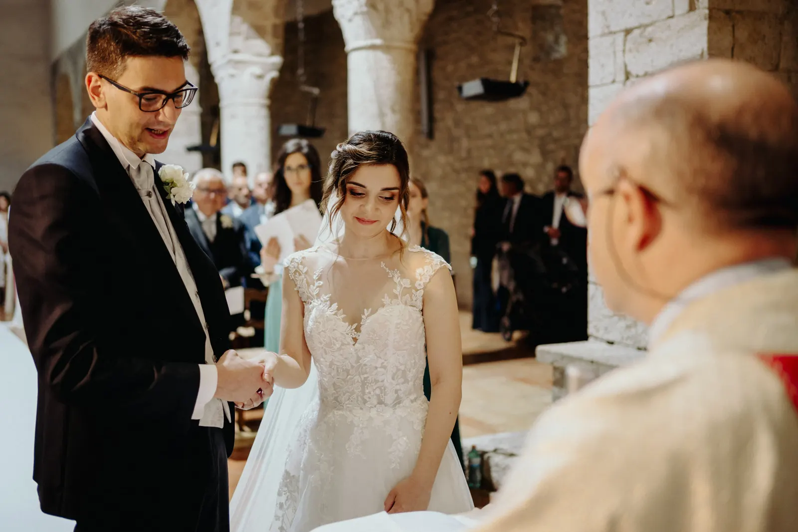 Gli sposi si tengono per mano davanti al sacerdote durante la cerimonia