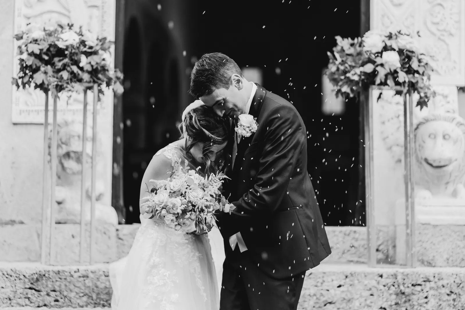 Il bacio degli sposi sul sagrato tra il riso, in bianco e nero