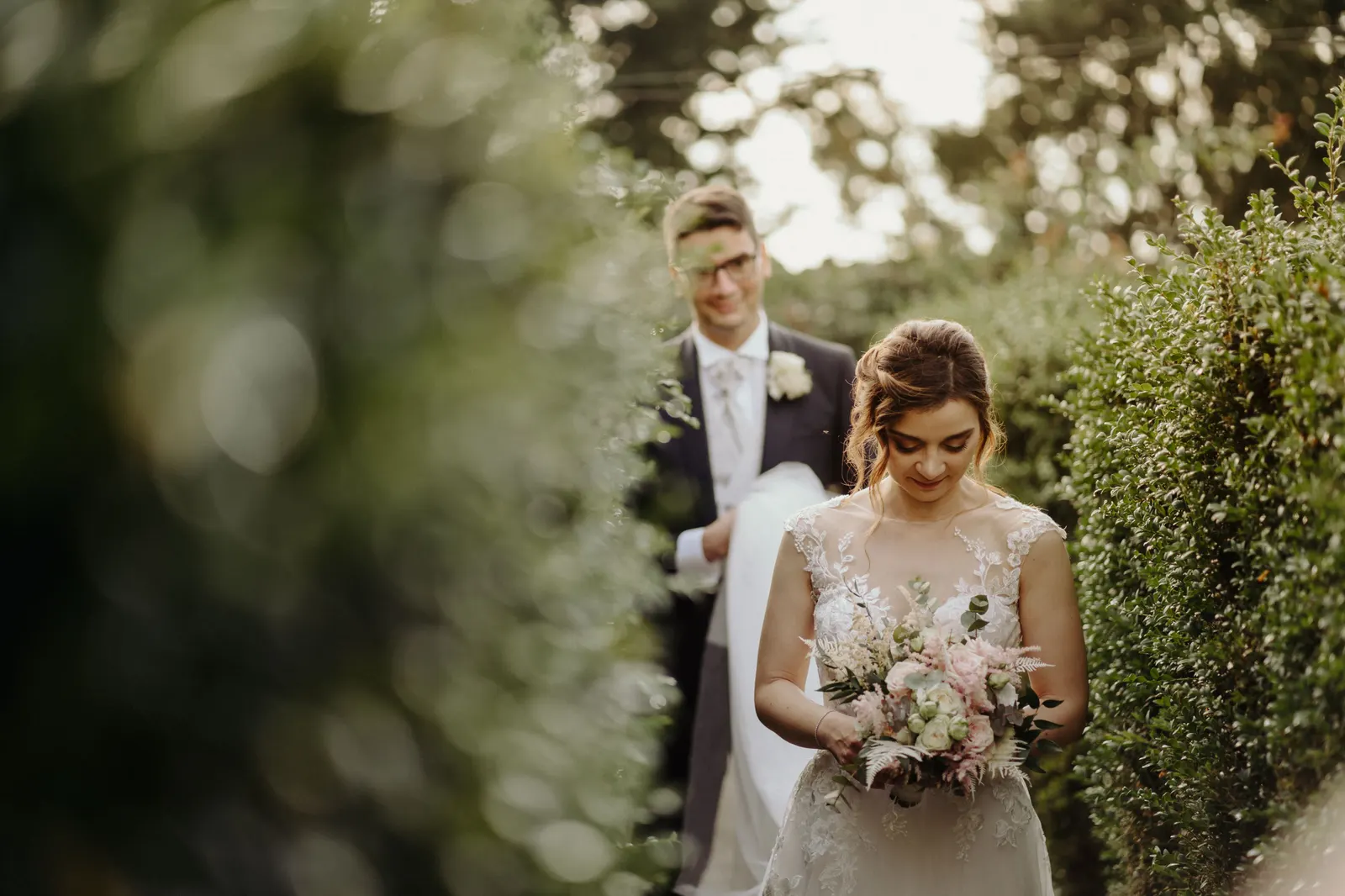 Gli sposi passeggiano tra le siepi del castello, lei con il bouquet in mano