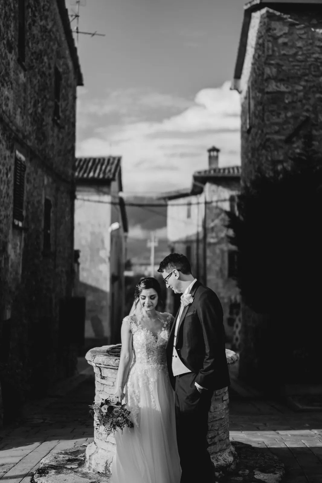 Martina e Daniele in un vicolo del borgo, con le colline sullo sfondo, in bianco e nero