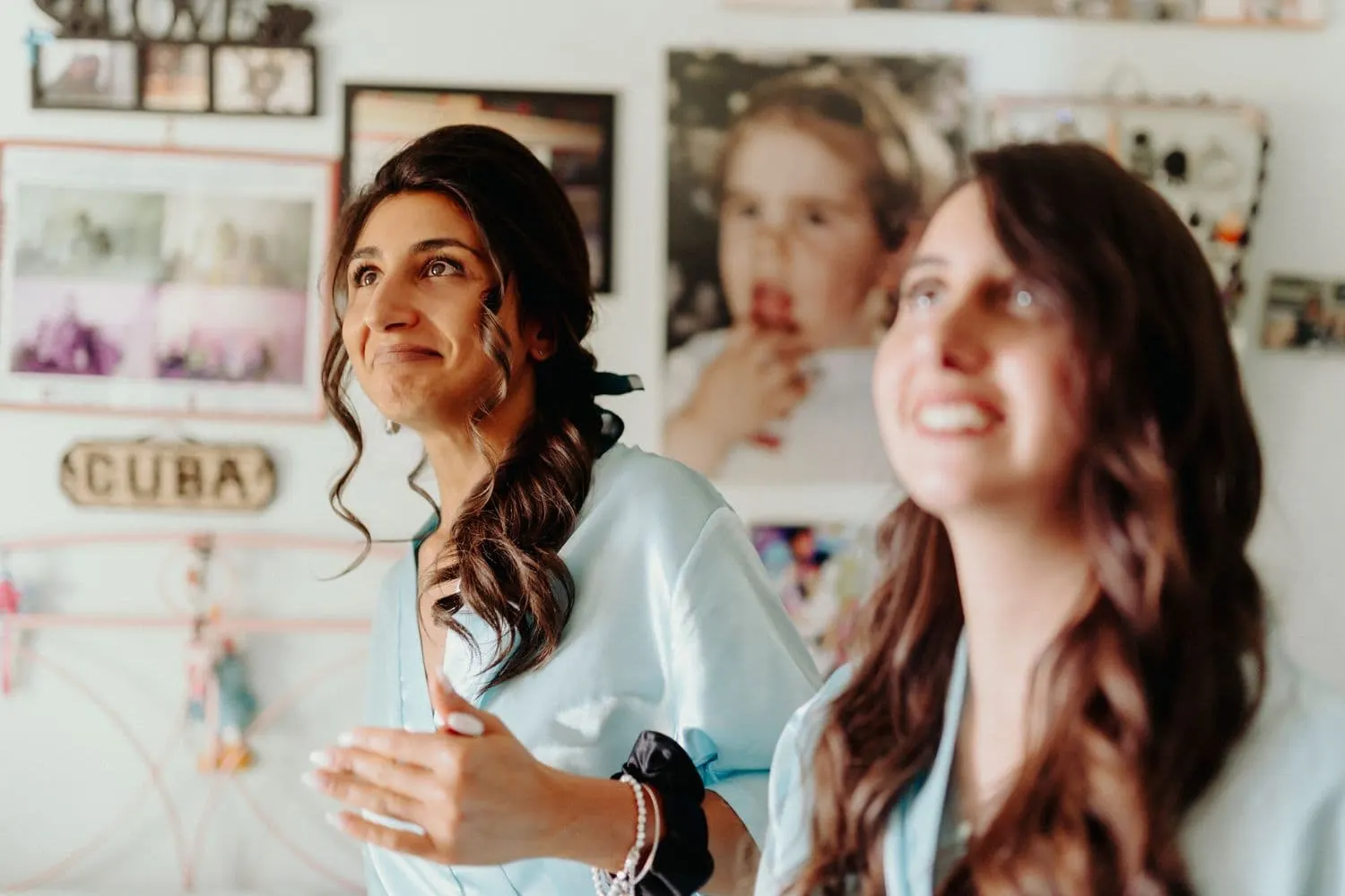 Micaela laughing with a friend while getting ready, in a mint-green robe