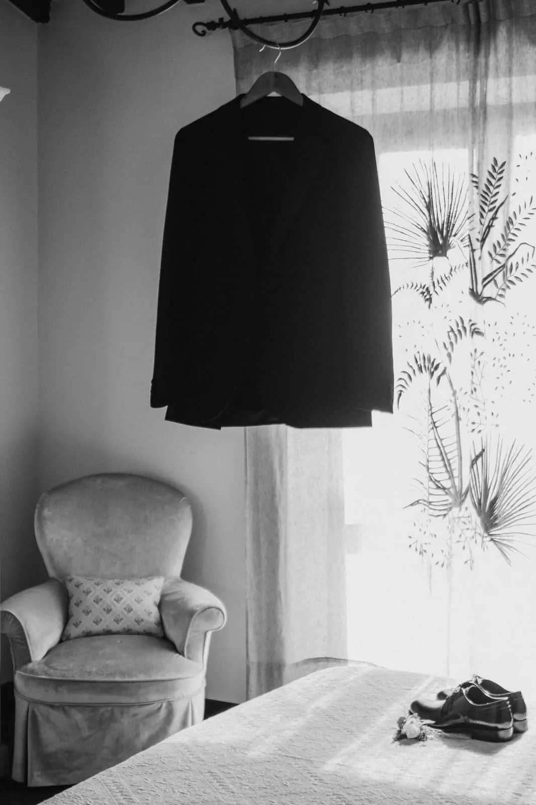 The groom's jacket hanging in front of the window, in black and white