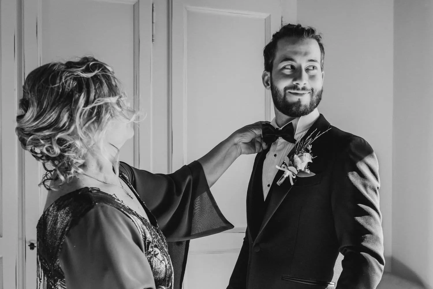 Raffaele's mother pinning the flower to his lapel, in black and white