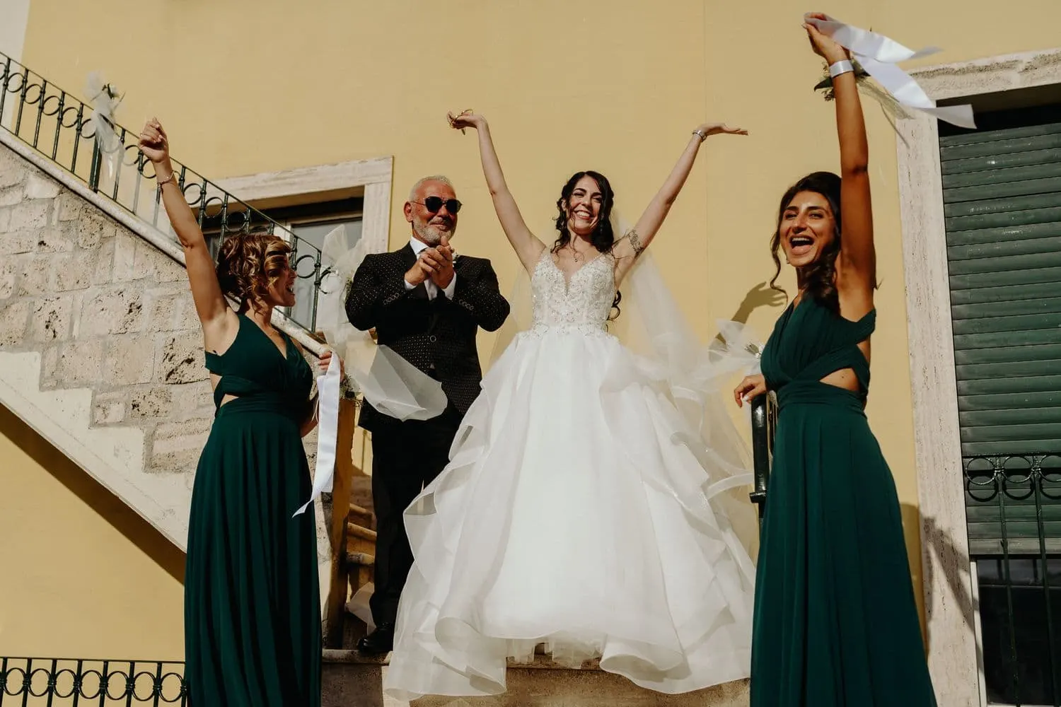 Micaela cheering with her arms raised as she leaves the house with her bridesmaids