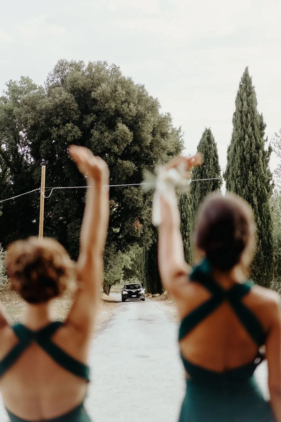 The bridesmaids seen from behind, waving as the bride arrives