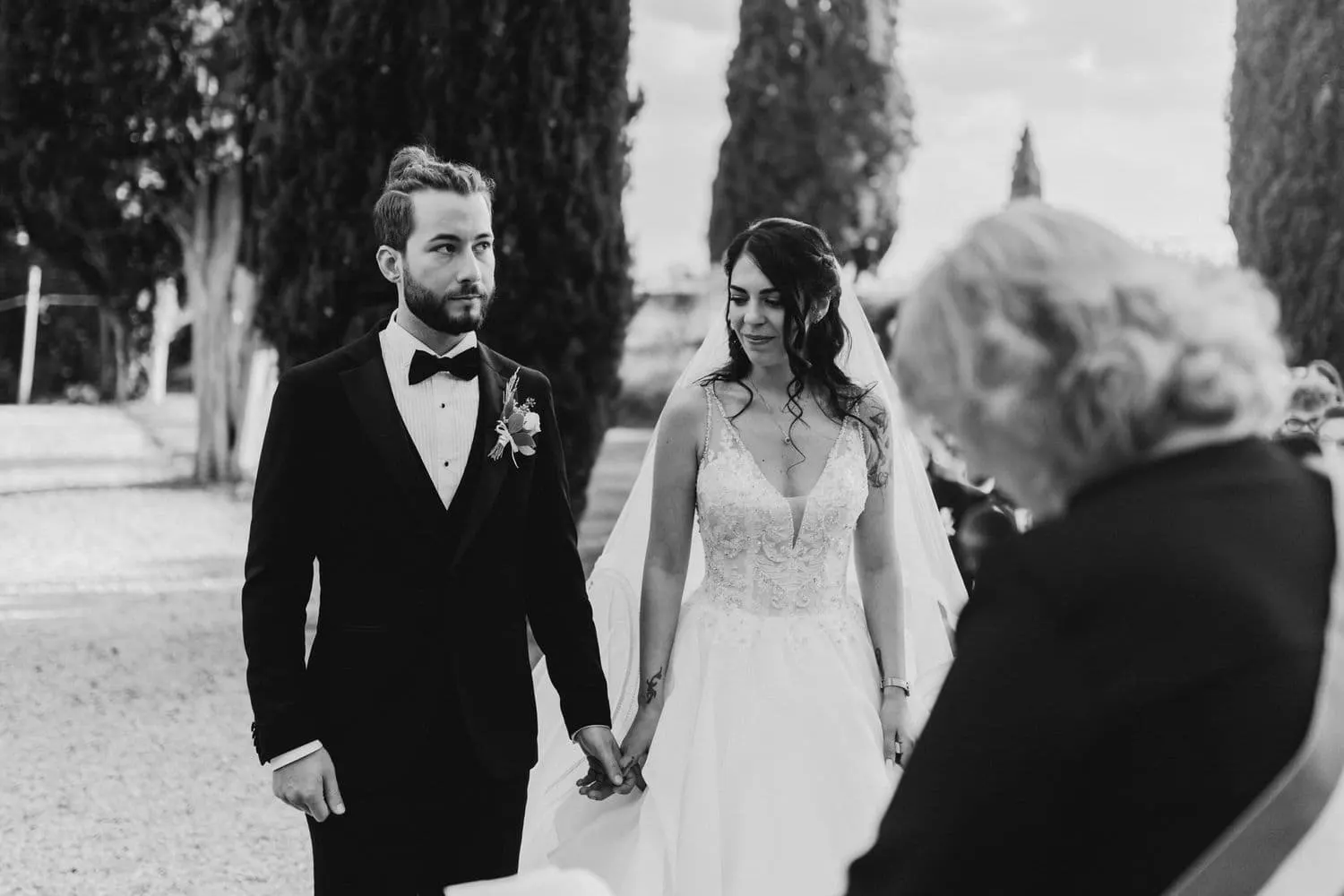 The couple hand in hand during the civil ceremony, in black and white