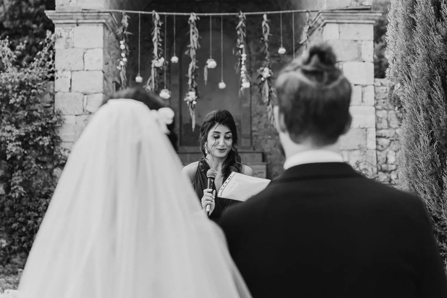 A reading during the ceremony, seen from behind the couple, in black and white