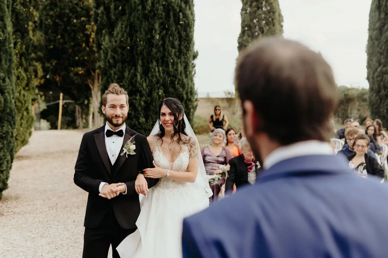 The couple arm in arm, listening to a friend during the ceremony
