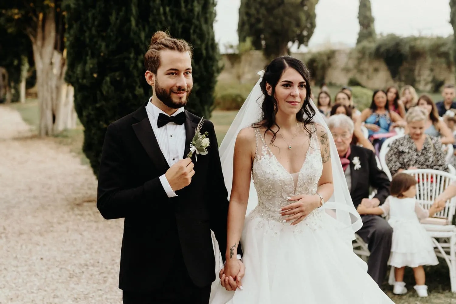 Raffaele and Micaela hand in hand during the ceremony among the cypresses