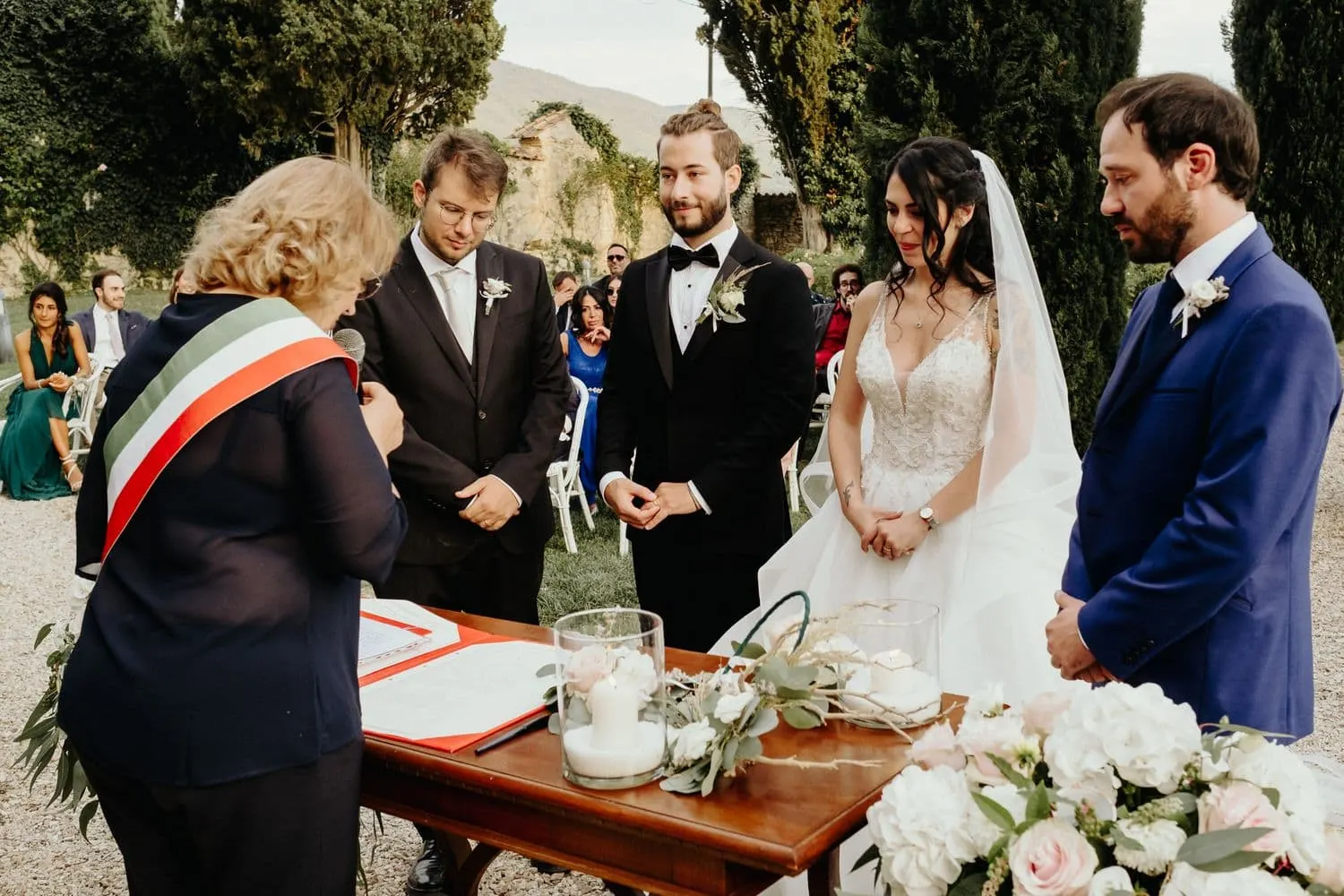 The couple and their witnesses at the signing table, with the officiant in the tricolour sash