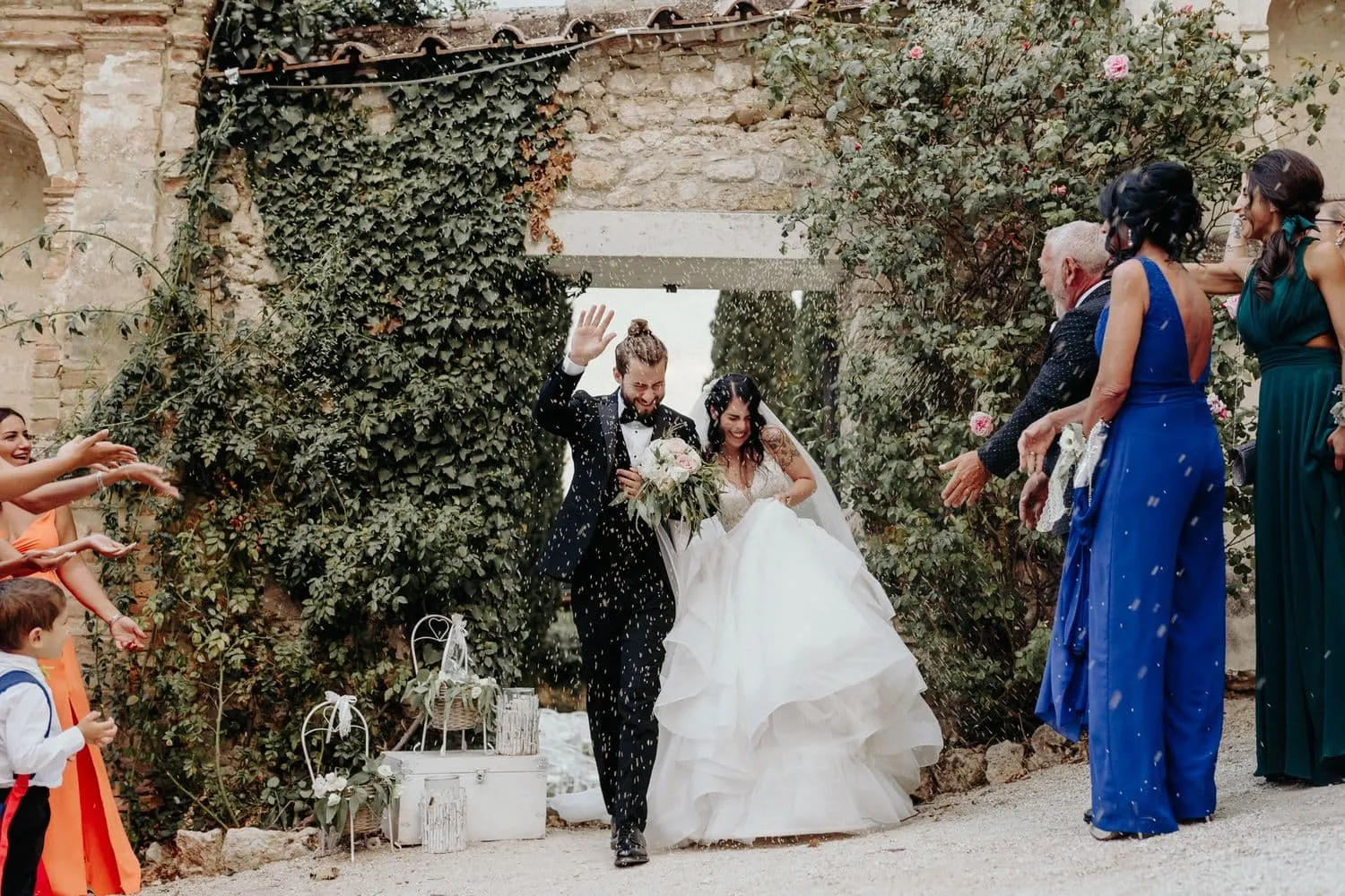 The couple's exit through petals along the ivy-covered wall