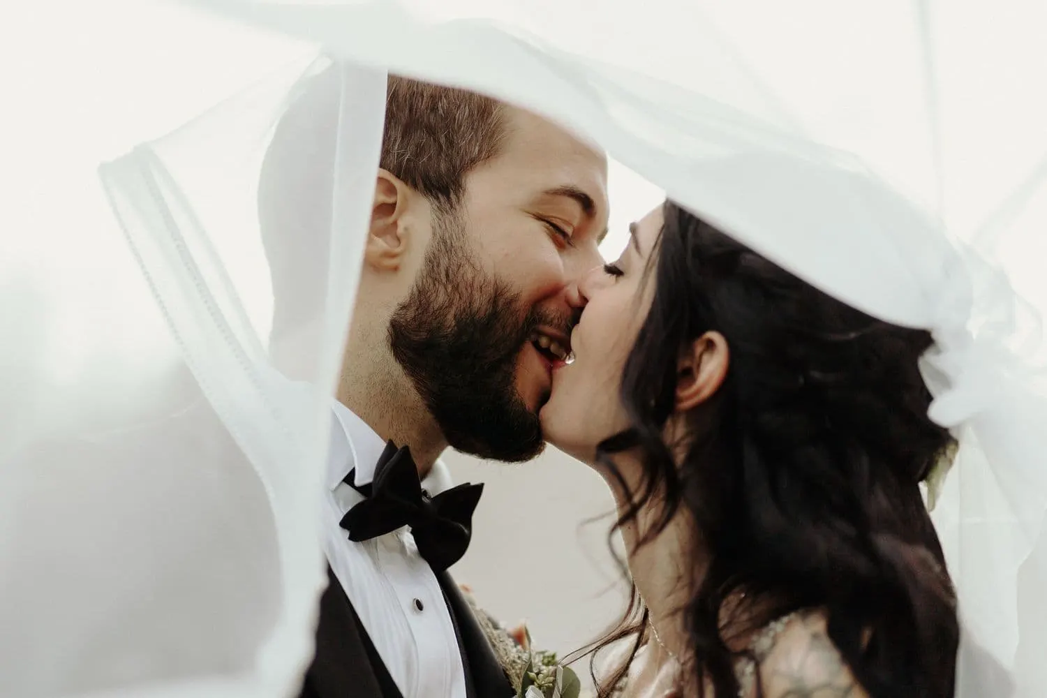 The couple kissing under the veil