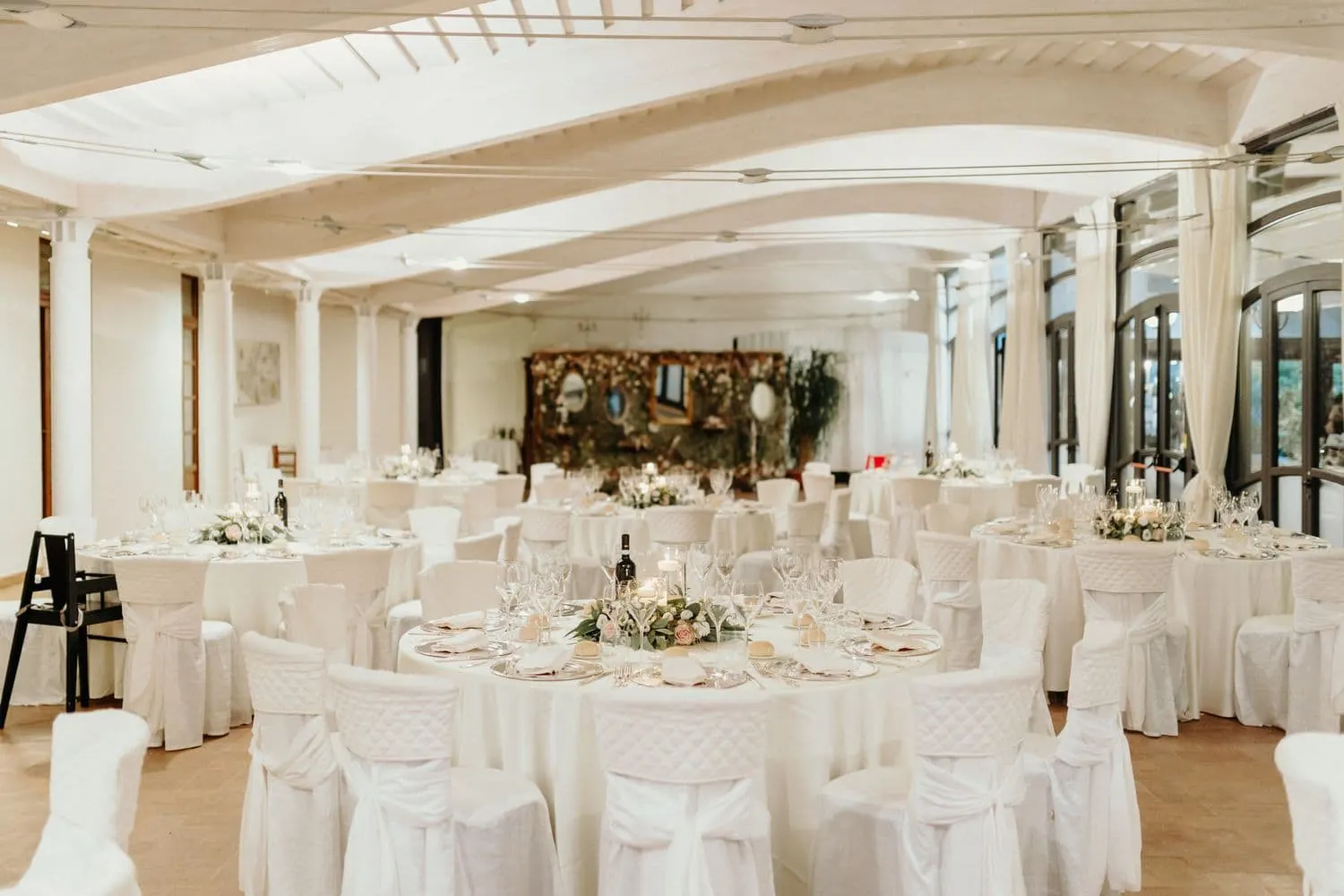 The reception hall with round tables dressed in white