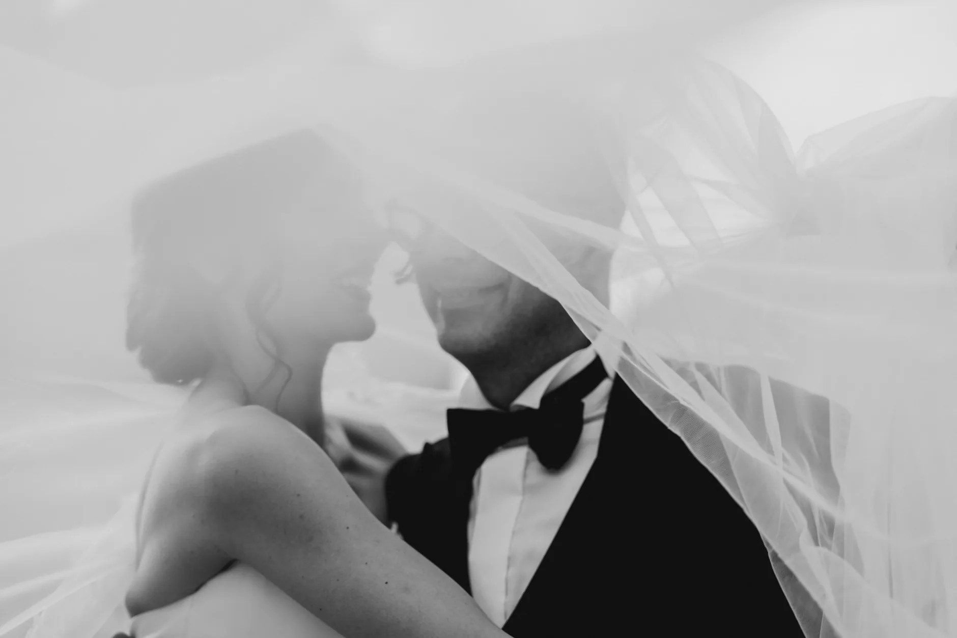 Gli sposi sotto il velo, a un passo dal bacio, in bianco e nero