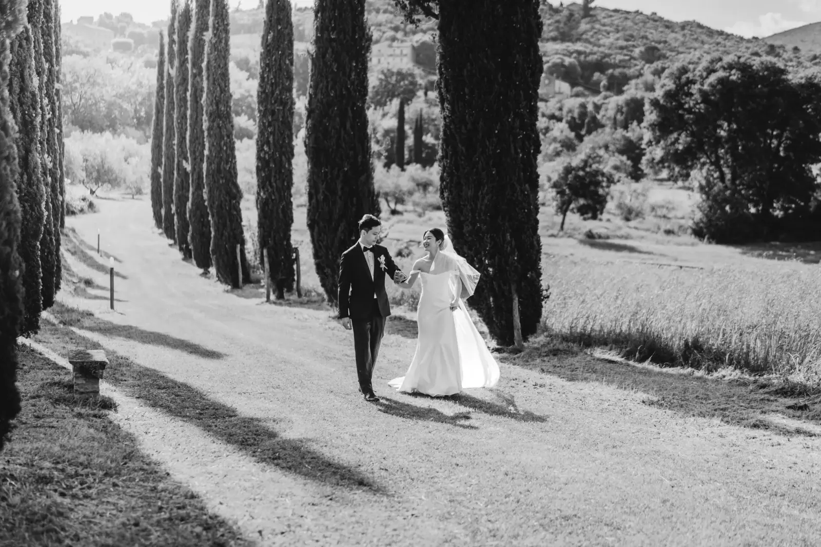 Gli sposi camminano nel viale dei cipressi della Tenuta del Gallo, in bianco e nero