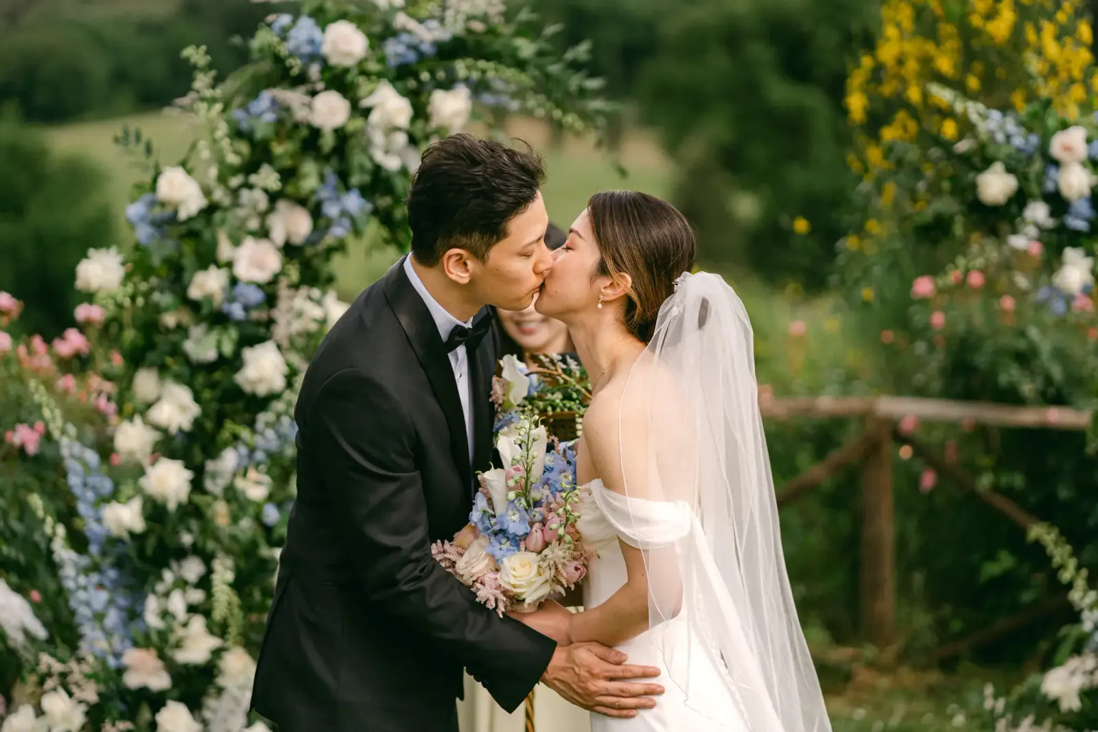 Il bacio degli sposi davanti all'arco di fiori azzurri e bianchi