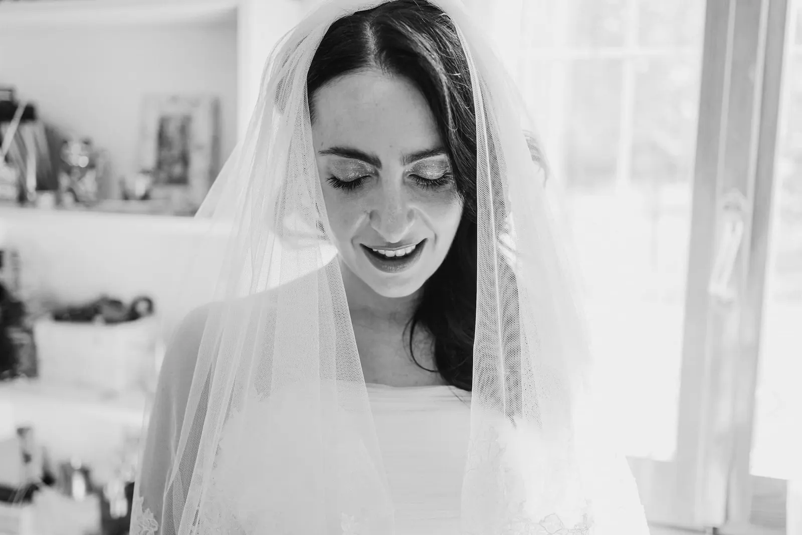 The bride smiling under her veil, in black and white