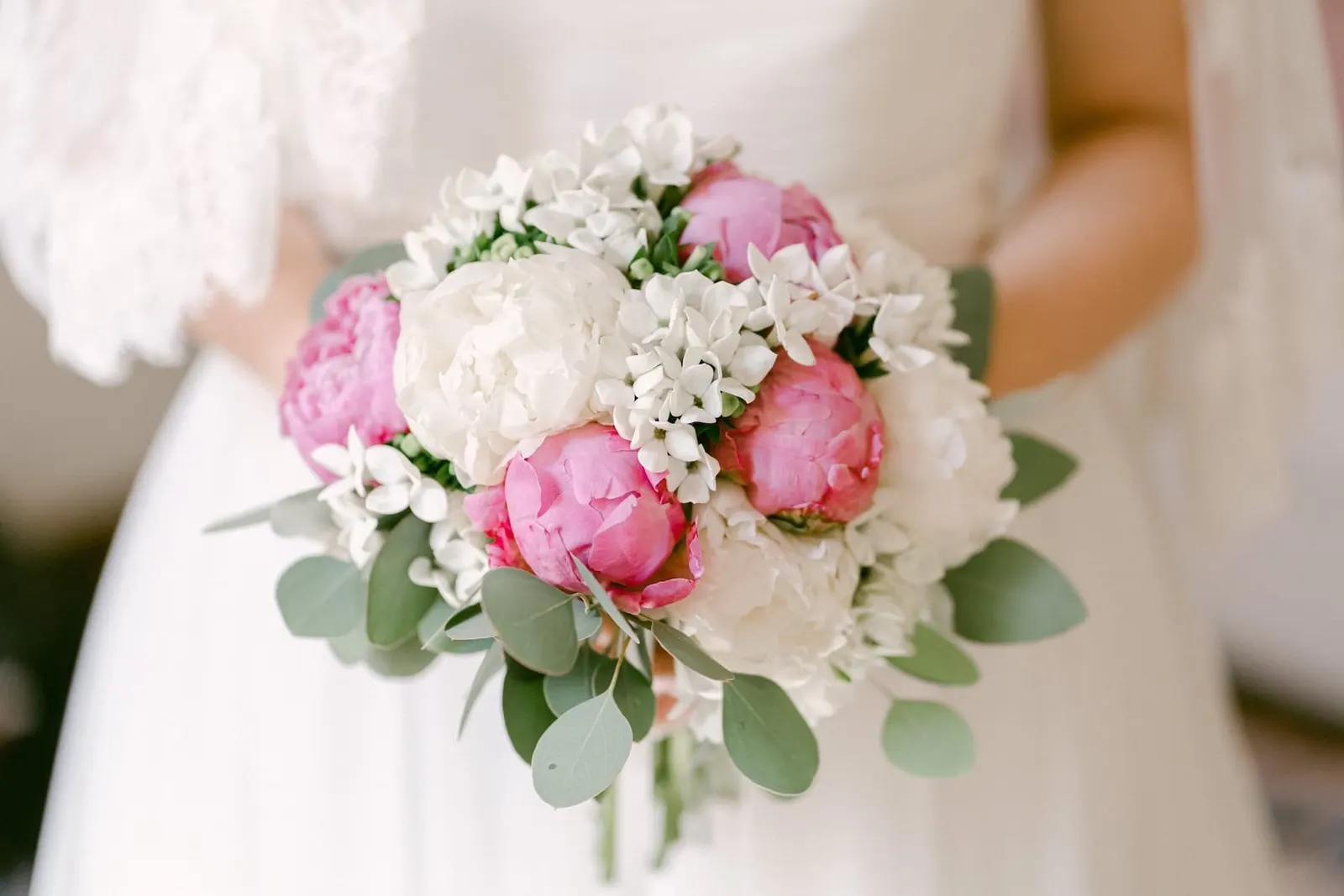 The bouquet of pink and white peonies in the bride's hands