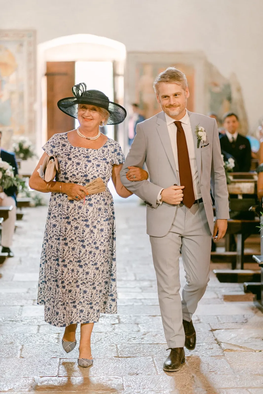 Thomas and his mother smiling as they walk down the nave