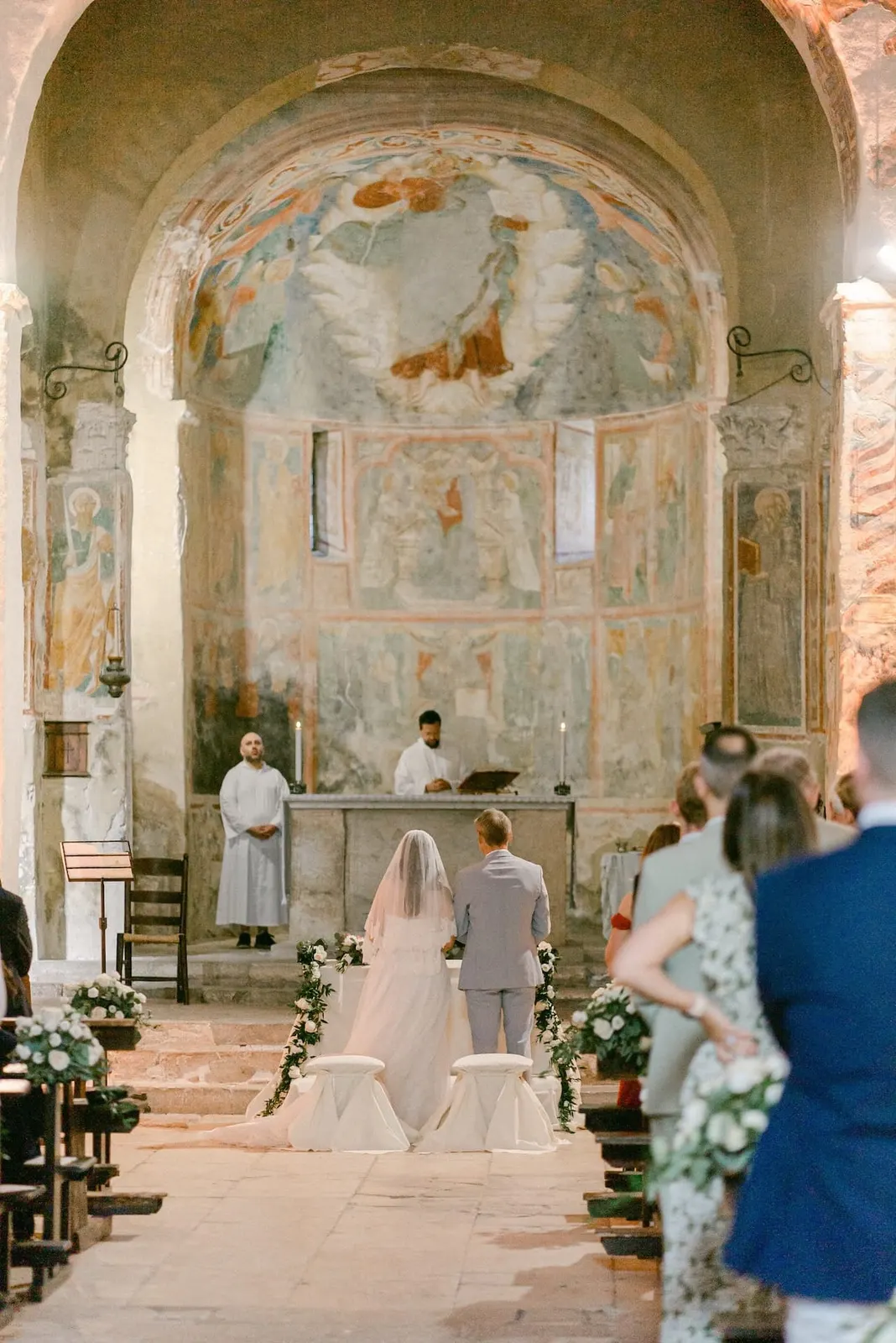 The couple seated before the altar under the frescoed apse