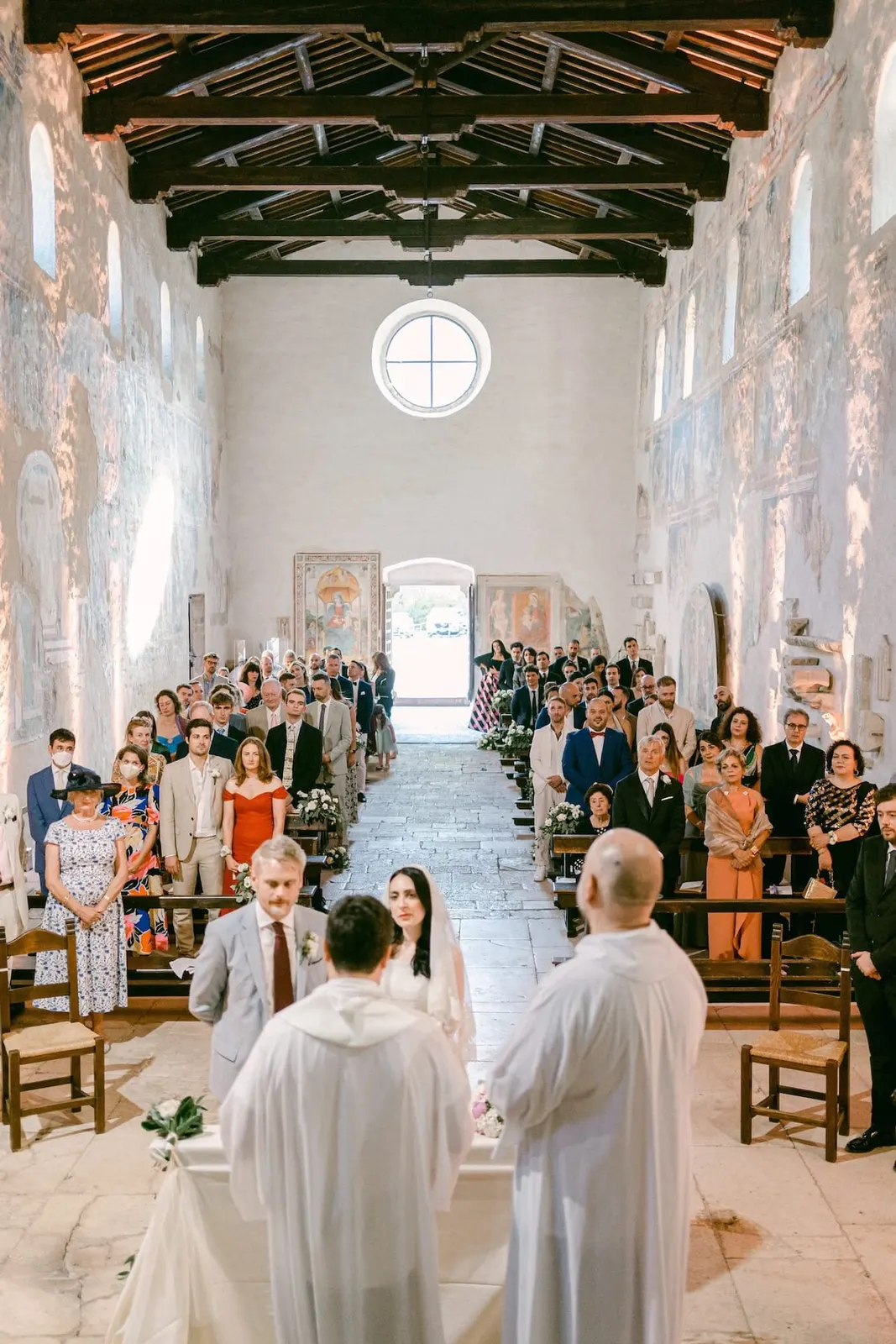 La navata vista dall'altare, con gli sposi davanti ai celebranti e gli invitati in piedi