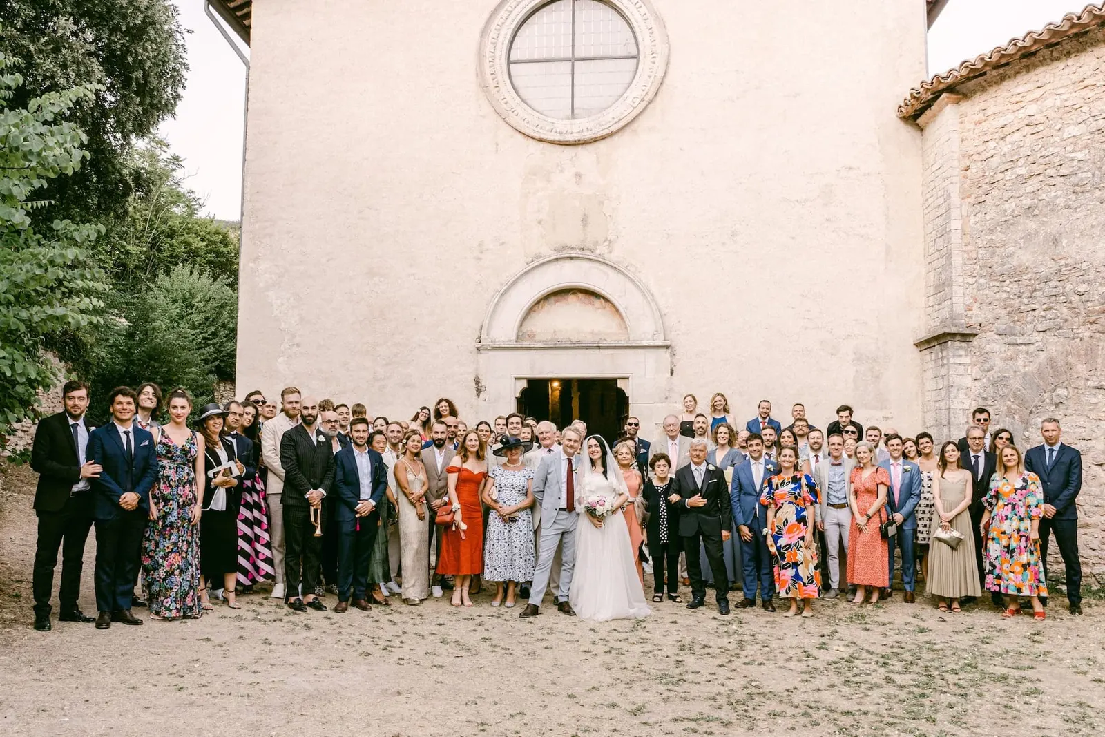 The group photograph of all the guests in front of the church façade