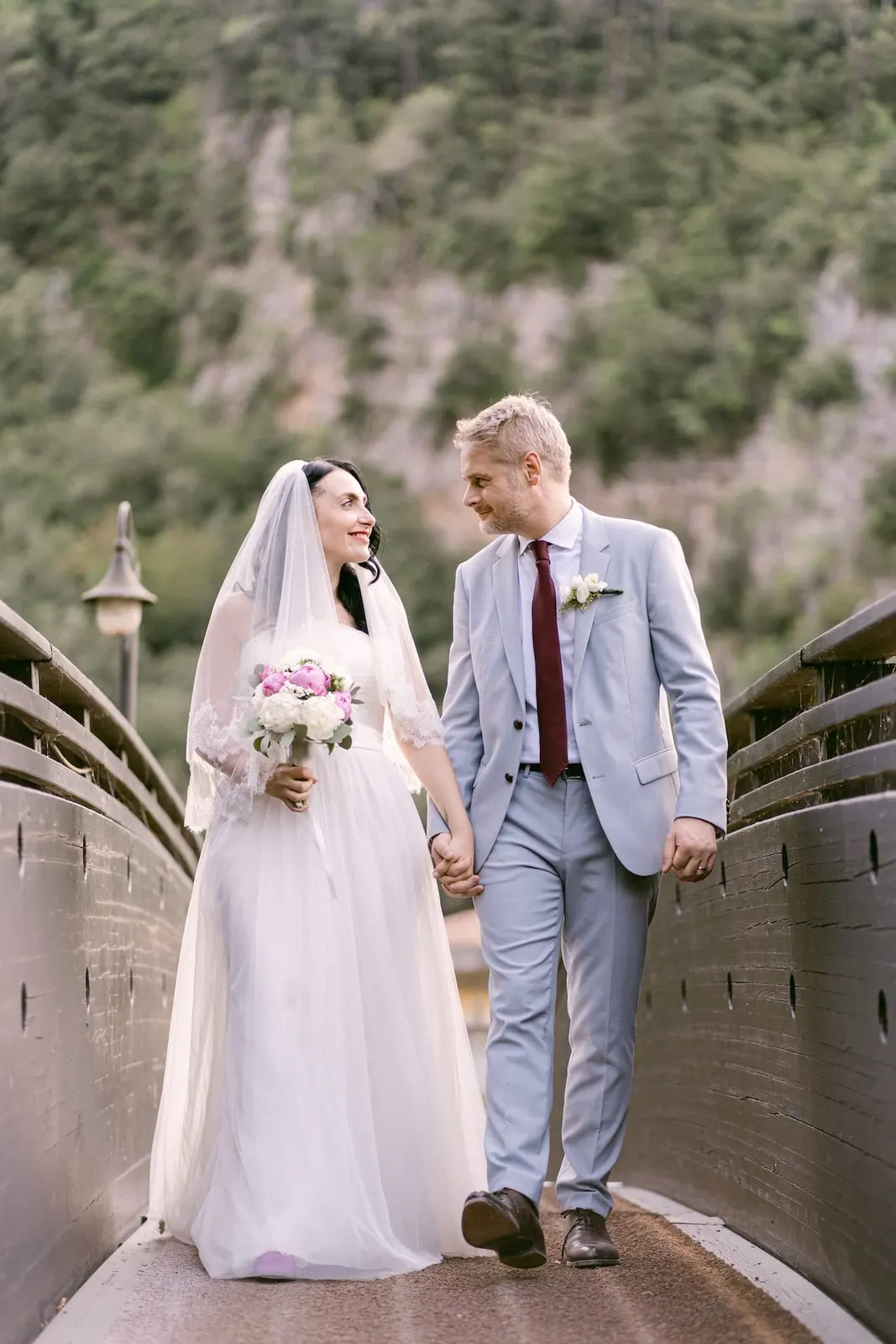 The couple walking hand in hand across the wooden bridge