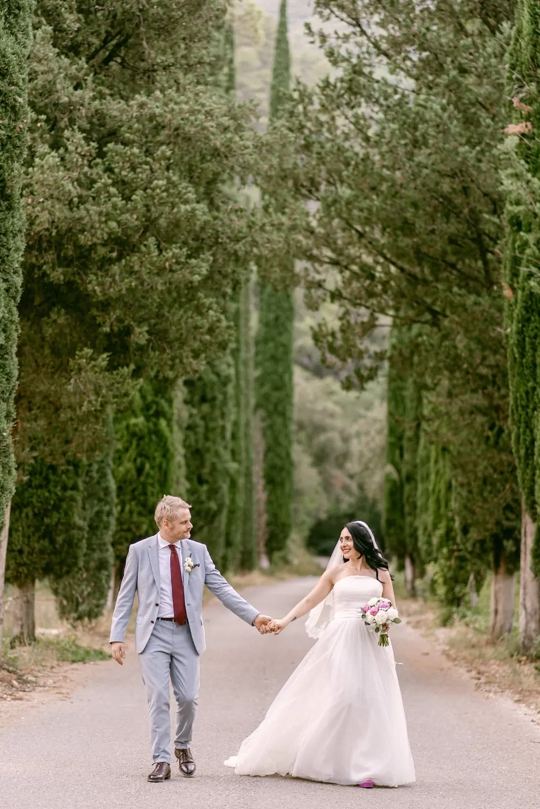 Valentina and Thomas walking hand in hand in the cypress avenue