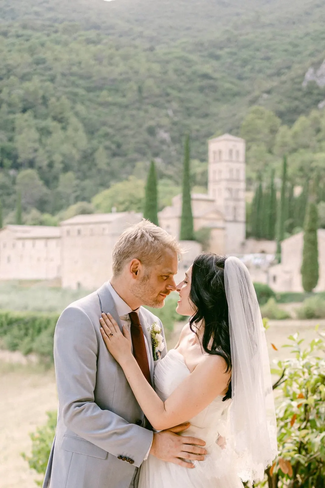 The couple embracing with Abbazia San Pietro in Valle and its bell tower behind them