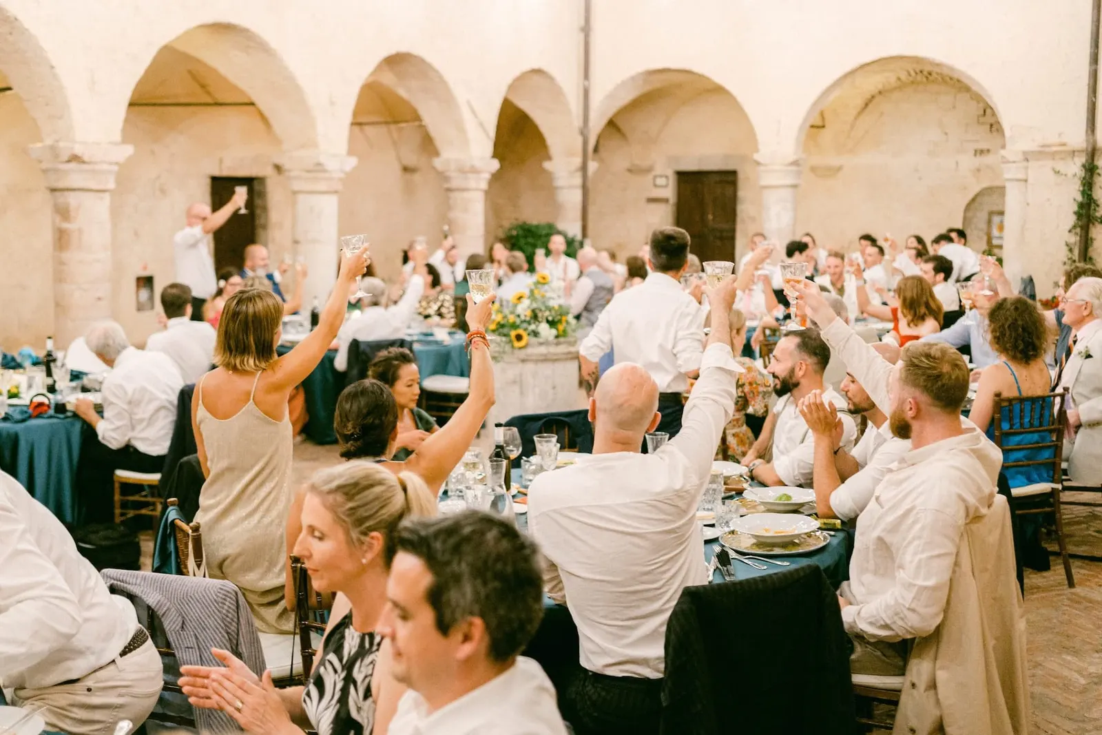 Guests cheering with raised arms at the tables in the cloister