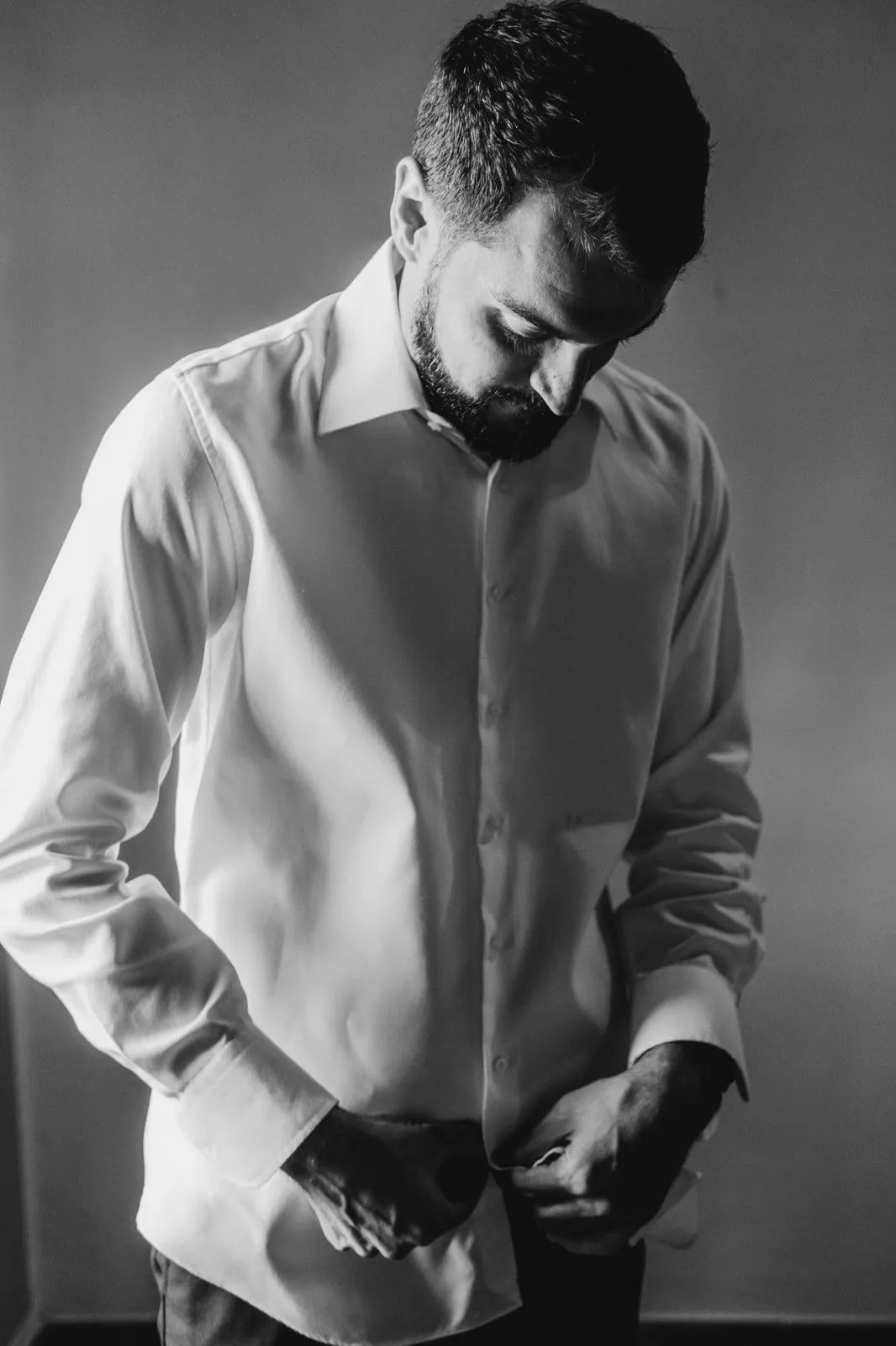 Francesco buttoning his shirt, in black and white
