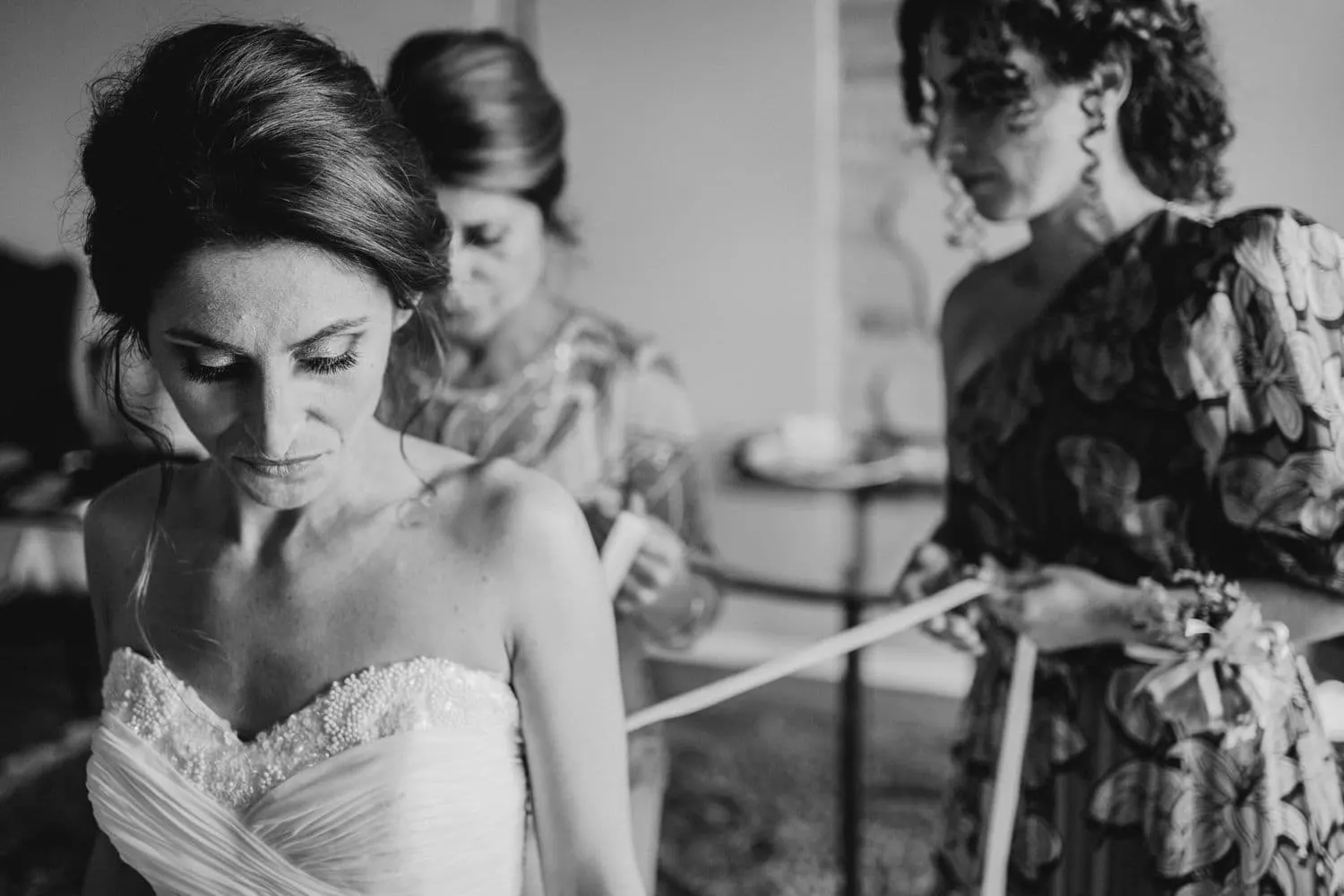 The bride as her dress is laced, in black and white