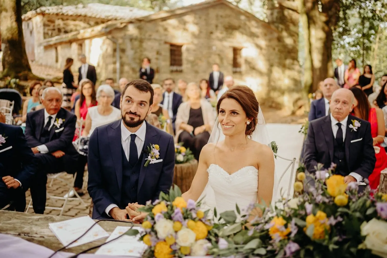 Giulia and Francesco smiling, seated at the ceremony table