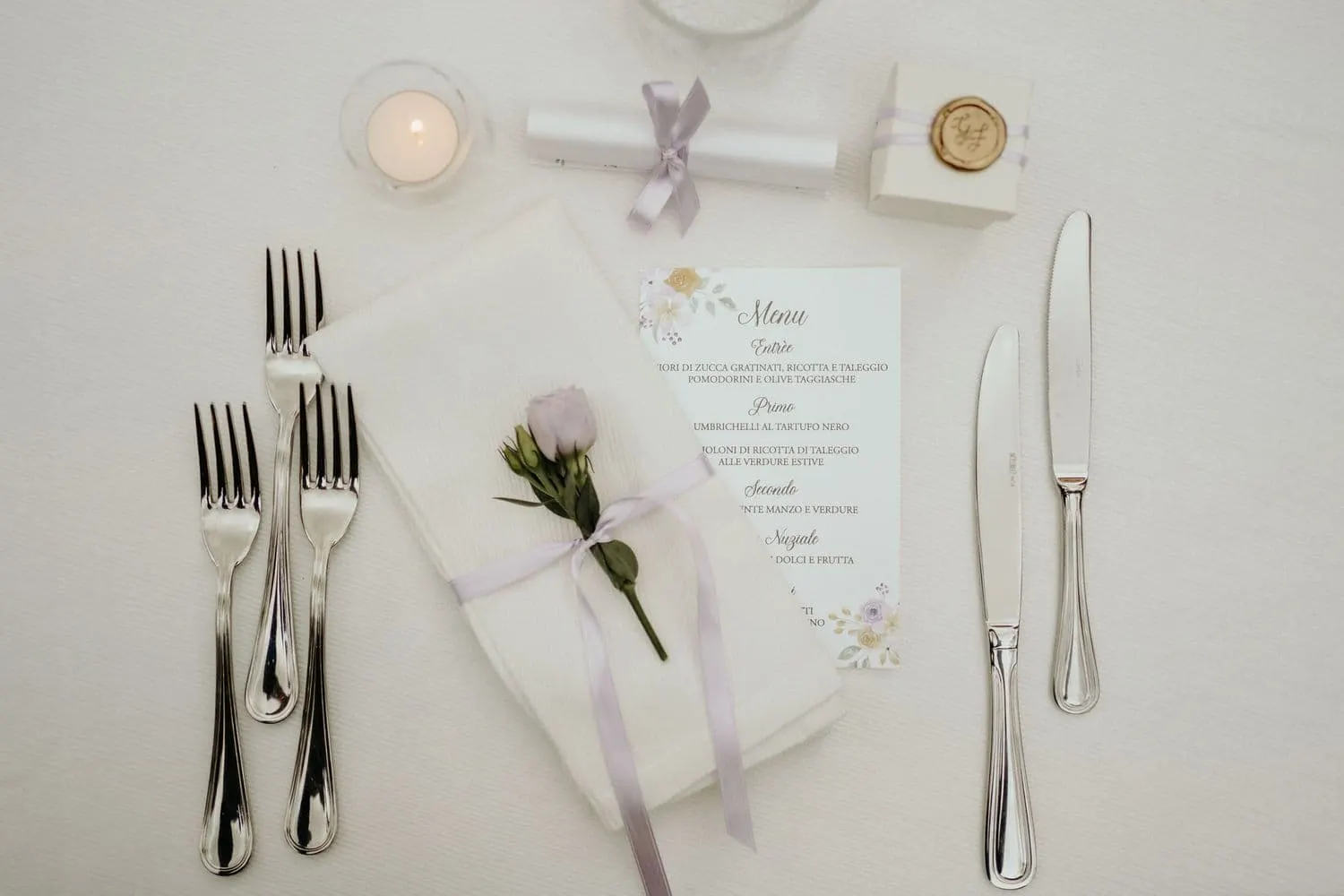 A place setting with the menu, a flower and the cutlery