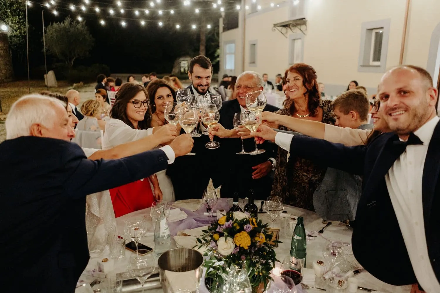 A toast at one of the guests' tables under the string lights at Villa Laura